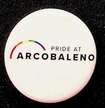 White circular badge with black font reading "Pride at Arcobaleno" and a rainbow graphic.